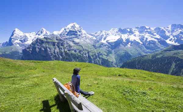Traveler siting on the wooden bench looking to beautiful mountain view  Murren  Switzerland shutterstock 495173056