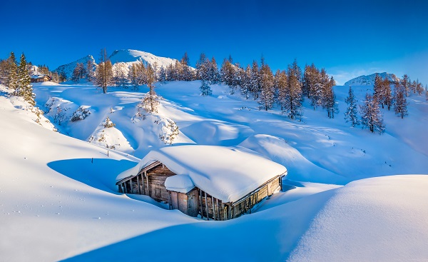 Panoramic view of beautiful winter mountain landscape with traditional mountain cabin in the Alps in golden evening light at sunset shutterstock 243462181