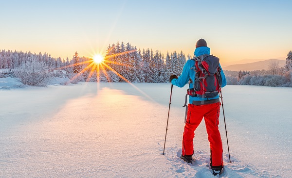 Snowshoe walker running in powder snow with beautiful sunrise light  Outdoor winter activity and healthy lifestyle shutterstock 568607152