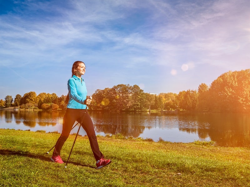 Nordic walking adventure and exercising concept - woman hiking withnordic walking poles in park. With light leak and lens flare_shutterstock_493512376.jpg